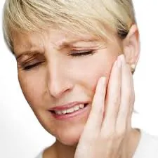 older woman with her hand near her face showing she is in pain
